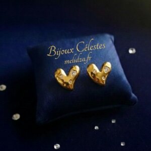 Boucles d'oreilles Cœur dorées sur son coussin bleu